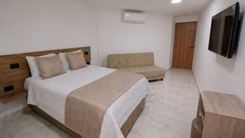 Una camera da letto con un letto, un divano, una TV e un armadio in legno.