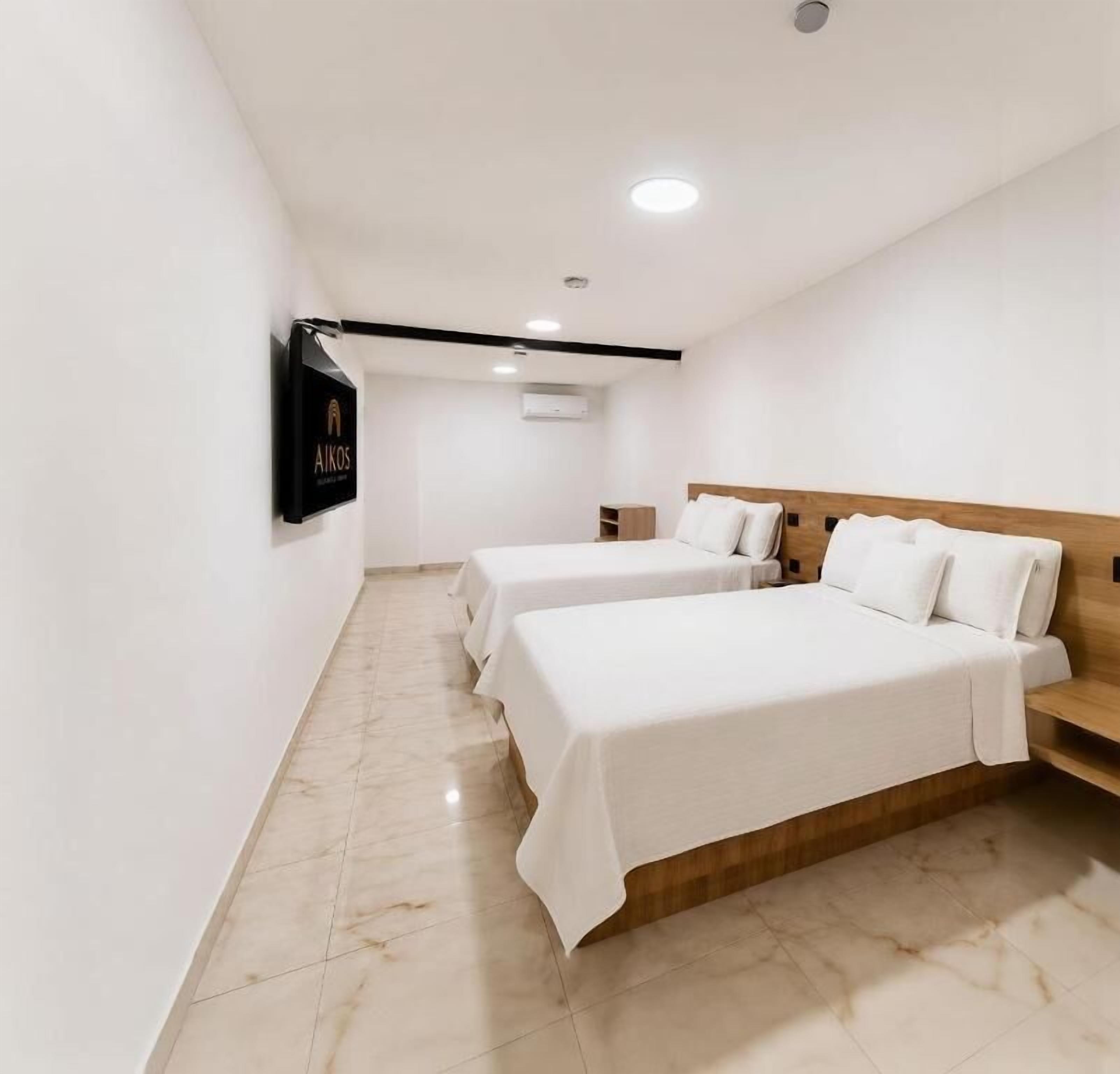 A hotel room with two beds, a flat-screen TV mounted on the wall, and a marble floor.