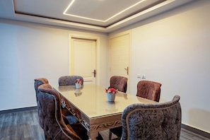 A conference room with a glass table, four chairs, and two doors.