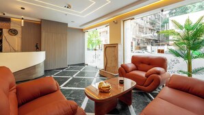 Un moderno vestíbulo con mostrador de recepción, asientos de cuero, una mesa de centro y amplias ventanas.