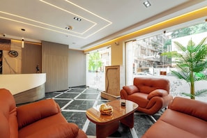 Eine moderne Lobby mit einer Rezeption, Ledersitzgelegenheiten, einem Couchtisch und großen Fenstern.