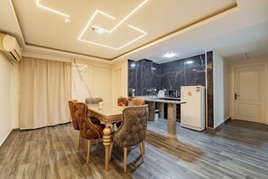 Eine moderne Küche mit Marmorarbeitsplatten, einem Einbaukühlschrank und einem Essbereich mit Holztisch und gepolsterten Stühlen.