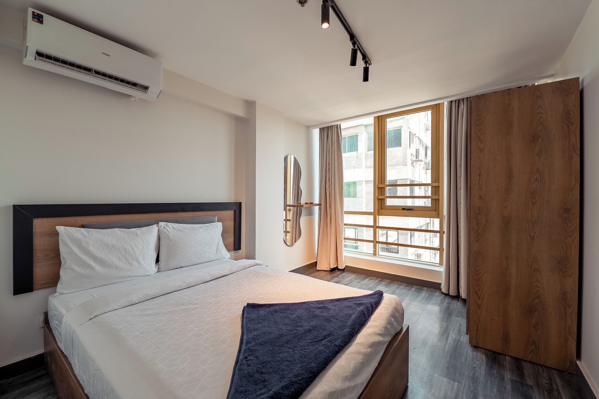Ein Hotelzimmer mit Bett, Klimaanlage, einem Vorhangfenster und Blick auf Gebäude.