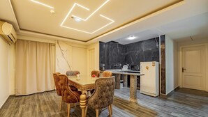 Cocina moderna con salpicadero de mármol, comedor con mesa y sillas, y un refrigerador independiente.