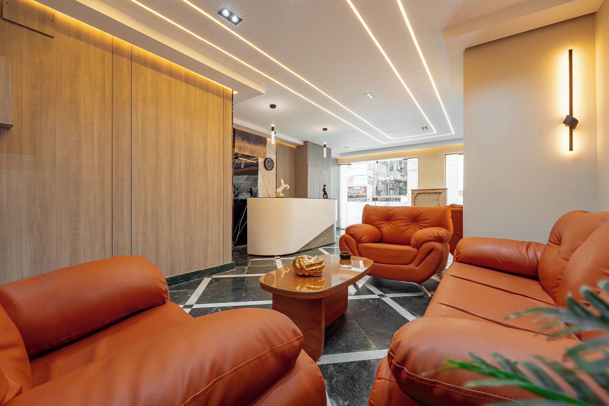 A modern lobby with leather sofas, a reception desk, and a marble floor.