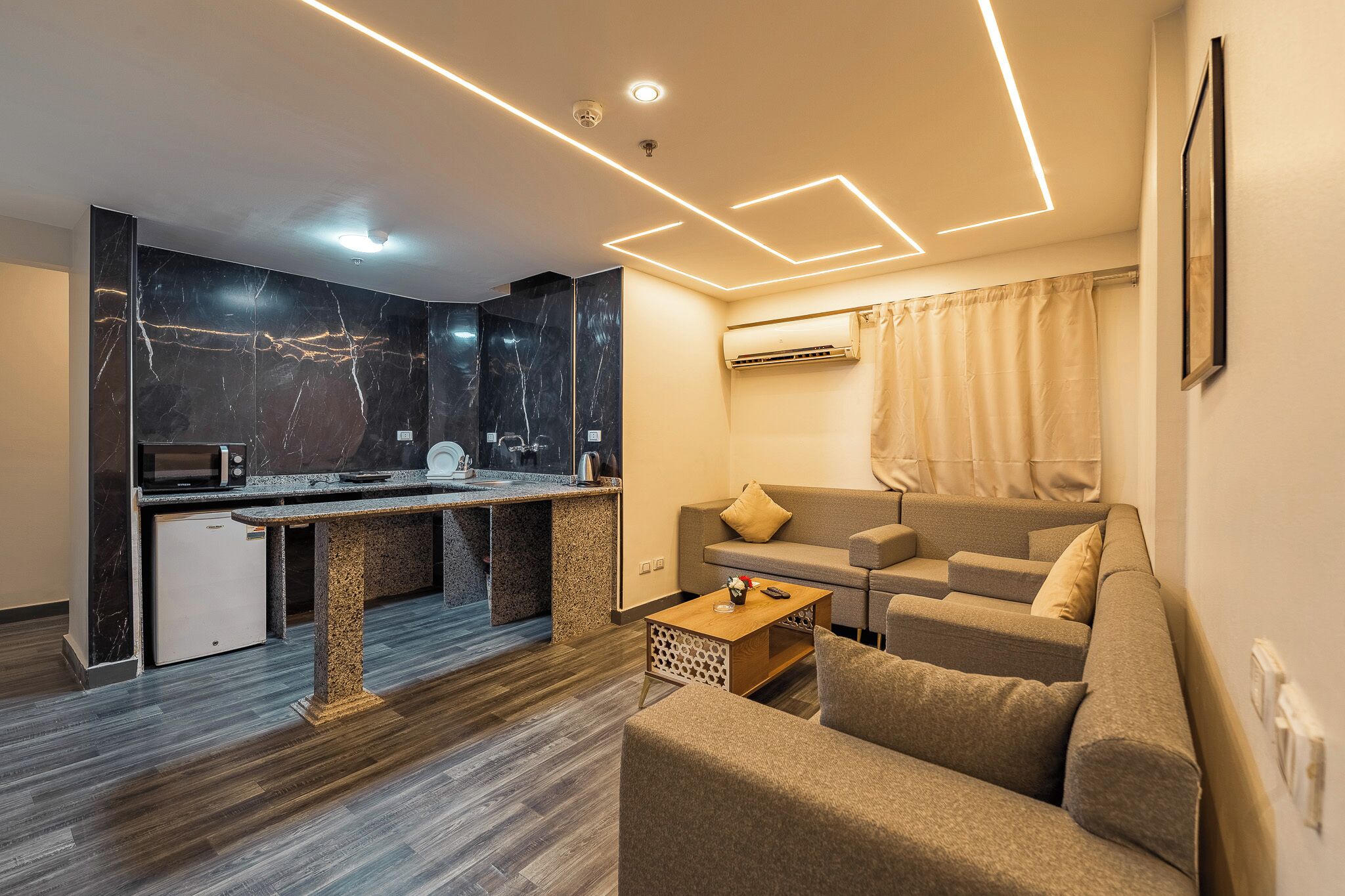 Um espaço de estar moderno com cozinha, sofá e mesa de centro.