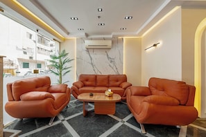 Un interior modern amb sofàs de pell, una paret de marbre i un aparell d'aire condicionat.