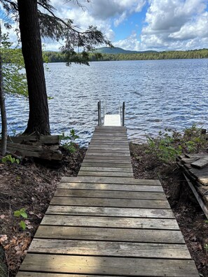 A wooden dock leading to a lake with a forested shoreline.
