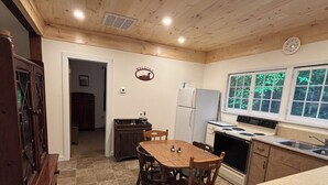 Una cocina con paneles de madera, una mesa de comedor, un refrigerador y una estufa.