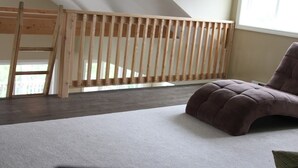 A room with a wooden crib, a cushioned chair, and a carpeted floor. - Charming 3-bedroom cottage in lovely Vinalhaven perfect for relaxing (Vinalhaven)
