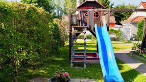 Une structure de jeu en bois, dotée d’un toboggan et d’échelons d’escalade.