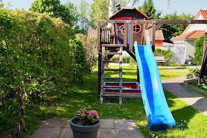 Eine hölzerne Spielanlage mit Rutsche und Kletterstufen.
