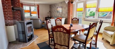 A dining area with a brick fireplace, wooden chairs, a table, and a sofa.