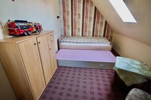 Ein kleines Schlafzimmer mit Etagenbett, einem Holzschrank, einem kleinen Tisch mit Tischdecke und einem Oberlicht.