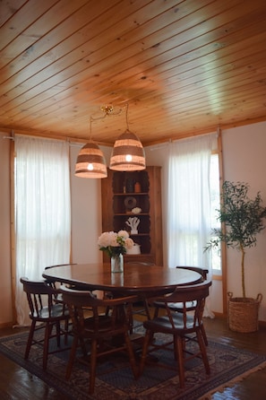 Un espace repas avec une table en bois, des chaises et des lampes suspendues.