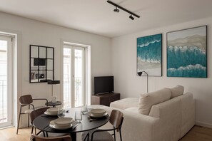 Ein modernes Wohnzimmer mit Essbereich, einem Flachbildfernseher und Kunstwerken an den Wänden.