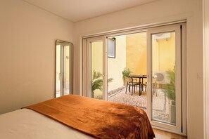 Ein Schlafzimmer mit Bett, eine Schiebetür zu einer Außenpatio mit Tisch und Stühlen.