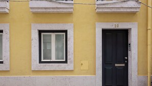 En bygning med en gul facade, en sort dør med nummer 10, og et vindue med hvid ramme.