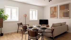 En moderne stue med spisebord, stole, sofa, fjernsyn og billedkunst på væggene.