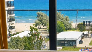 Un sofá color arena en una habitación con un ventanal que da a una playa y al océano.
