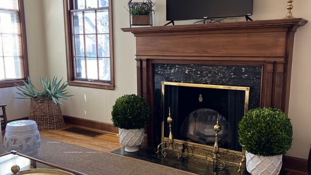 A living room with a fireplace, a television on the mantel, and a glass coffee table. - Beautiful Duplex in the heart of Lexington (Lexington)