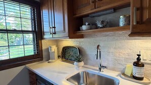A kitchen with wooden cabinets, a stainless steel sink, a toaster, and a window with blinds. - Beautiful Duplex in the heart of Lexington (Lexington)
