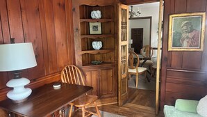 A wooden-paneled room with a dining table, chairs, a lamp, a bookshelf, and a door leading to another room. - Beautiful Duplex in the heart of Lexington (Lexington)