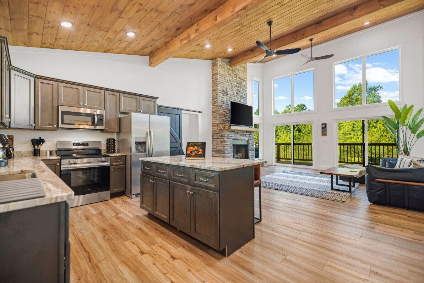 A spacious kitchen with modern appliances, a stone fireplace, and a large island.