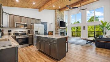 A spacious kitchen with modern appliances, a stone fireplace, and a large island.