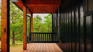 Eine Holzterrasse mit schwarzer Brüstung, umgeben von Bäumen.