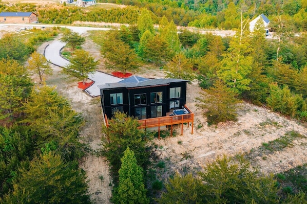 Una casa moderna de dos pisos con terraza, rodeada de un bosque denso.