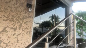 Una escalera que lleva a una entrada con puerta de vidrio, un portero automático en la pared y un cajero automático visible.