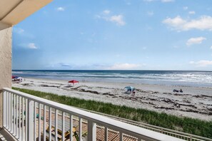 A beach with umbrellas and people, a wooden deck, and a view of the ocean. - Sunrise Views & Sandy Toes – Beachfront Ponce Inlet Condo (Ponce Inlet)