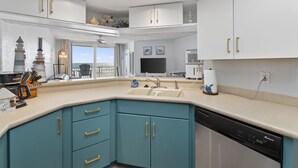 Una cocina moderna con lavavajillas, un fregadero y ventana con vistas a un balcón.