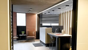 A modern office space with a desk, chair, and computer, a small table with a plant, and a window with blinds. - Depto. moderno y acogedor I Wifi I AC (Santiago)
