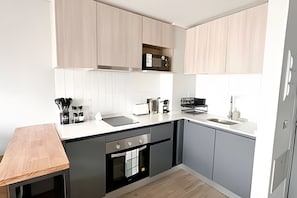 Une cuisine moderne avec une table en bois, un four encastré, un four à micro-ondes et un évier.