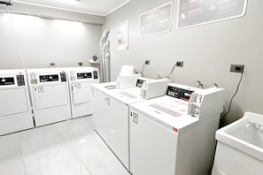 Une laverie moderne équipée de plusieurs machines à laver, d’un évier et d’un espace pour sécher le linge.