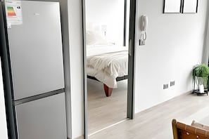 Quarto de hotel moderno com cama, telefone e uma pequena planta.