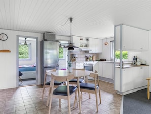 A modern kitchen with white cabinetry, a stainless steel refrigerator, a dining table with chairs, and a window providing natural light. - "Elif" - 200m from the sea by Interhome (Nordborg)