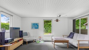 A room with white paneled walls, a wooden ceiling, a television, a sofa, a table, and a map on the wall. - "Elif" - 200m from the sea by Interhome (Nordborg)