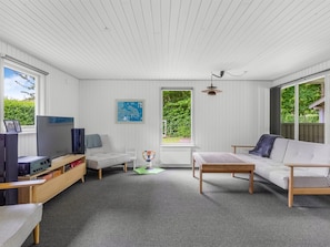 A room with white paneled walls, a wooden ceiling, a television, a sofa, a table, and a map on the wall. - "Elif" - 200m from the sea by Interhome (Nordborg)