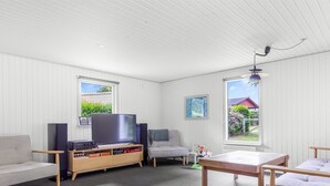 A room with a TV, speakers, a sofa, a table, and two windows with a view of greenery. - "Elif" - 200m from the sea by Interhome (Nordborg)