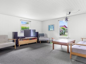 A room with a TV, speakers, a sofa, a table, and two windows with a view of greenery. - "Elif" - 200m from the sea by Interhome (Nordborg)