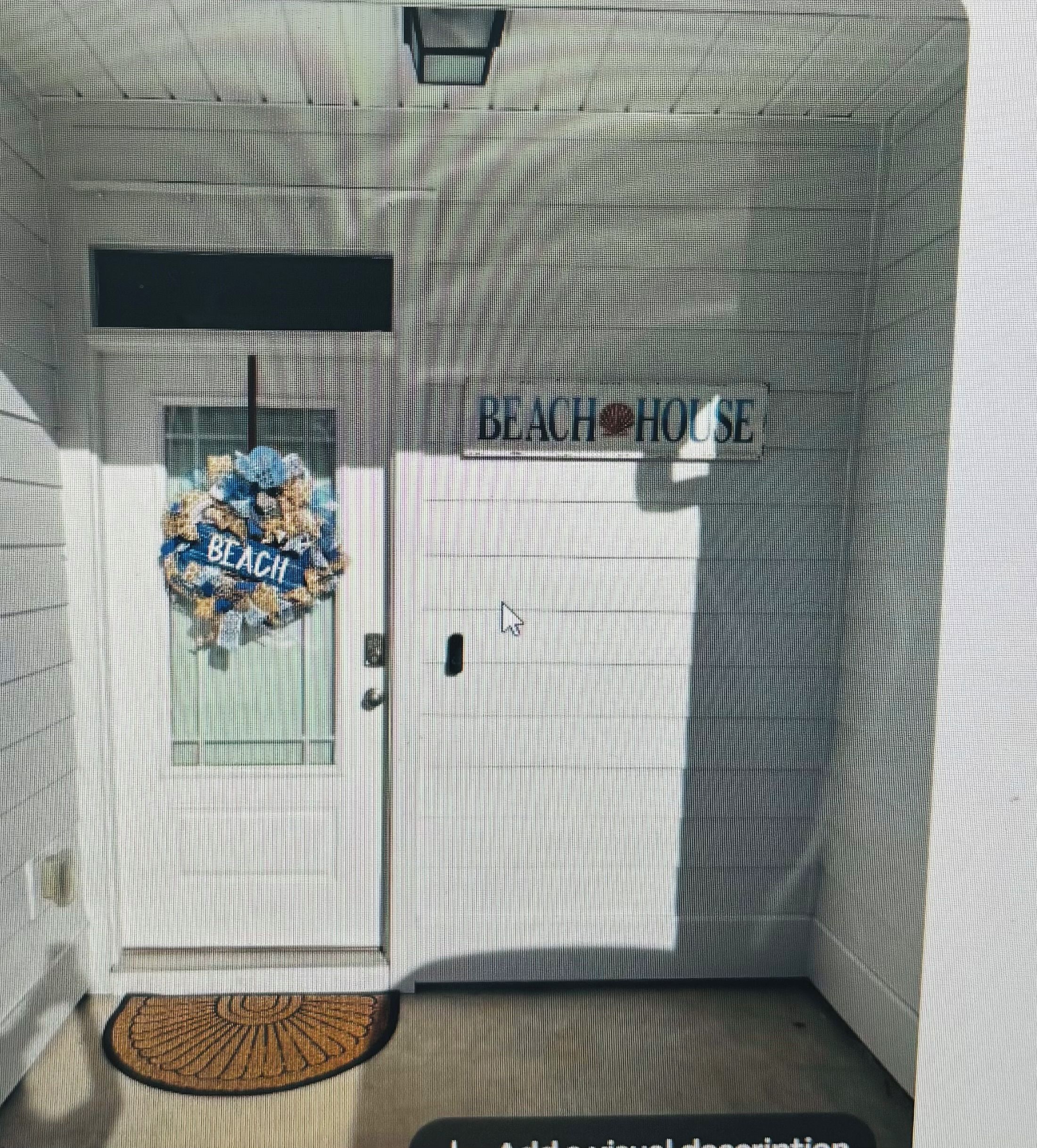 A door with a 'BEACH HOUSE' sign, a doormat, and a window with a wreath.