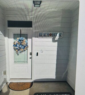 A door with a 'BEACH HOUSE' sign, a doormat, and a window with a wreath. -  Seaglass Sassy’s Beach House Your Santa Rosa Beach Escape (Santa Rosa Beach, Florida)