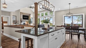 Una cocina moderna con una isla central, armarios blancos y un amplio ventanal con vistas al exterior.