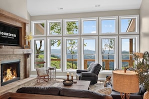 Amplia sala de estar con chimenea, ventanas grandes, un área de estar acogedora y vistas al exterior.