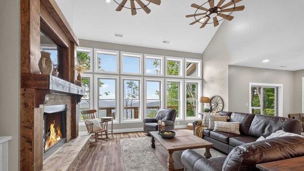 Un salón amplio con chimenea, muebles de cuero, ventanas grandes y vistas al exterior.