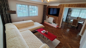 A modern living room with a sofa, TV, and dining area. - Lovely Clydebank Apartment - 2 Bedrooms (Clydebank)
