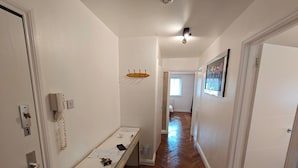 A hallway with a white telephone, a desk with papers, and a door marked with the number 1. - Lovely Clydebank Apartment - 2 Bedrooms (Clydebank)
